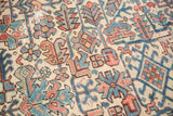 Pops of sky blue and faded red geometric motifs on an ivory distressed Heriz rug.