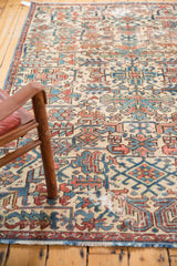 Distressed Heriz fragment rug with worn texture, geometric motifs in ivory, blue, and faded red.