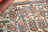 Distressed vintage Heriz carpet close-up, compact ivory, blue, red floral motifs and wear.