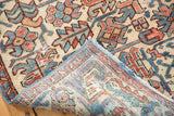 Distressed Heriz rug, ivory, blue, red geometric patterns, with visible knot head wear.