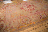 Lower right border of vintage Oushak carpet with secured edge, pale gold, red motifs.