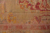 Detail of vintage Oushak rug with time-softened saffron, raspberry red motifs.