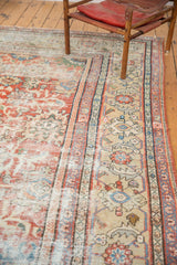 Distressed texture, madder red field, and camel palmette border of this antique Mahal rug.