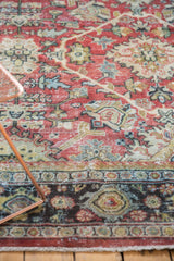 Distressed vintage Mahal rug border featuring intricate ruby red, navy, and ivory patterns.