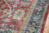 Textured vintage Mahal rug, showing decorative wear on ruby red field and blue floral border.