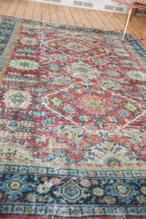 Distressed texture of a Vintage Mahal carpet's ruby red field and geometric navy border.