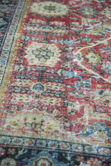 Distressed pile of Mahal carpet shows ruby red, blue, ivory patterns, and foundation.