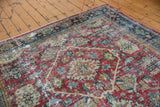 Distressed vintage Mahal carpet section: ruby red field, navy border, and visible foundation wear.