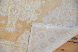 Distressed cotton Kayseri rug corner showing hand-knotted foundation, ivory fringe, and pale gold patterns.