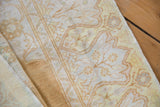 Distressed cotton pile texture with faded gold saffron and ivory ornate patterns.