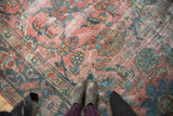 Distressed vintage Mahal rug texture showing faded blush, teal, and gold floral patterns.