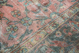Distressed pile of the vintage Mahal rug, with faded blush and teal floral patterns.