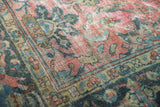 Faded cranberry, dusty teal, and gold vinery in a distressed vintage Mahal rug corner.