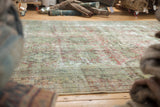 Distressed texture of vintage Mahal carpet with faded green, red, and exposed foundation.
