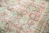 Distressed aesthetic of vintage Mahal carpet, faded red and seafoam green roundels, worn pile.