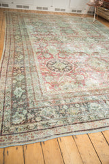 Faded seafoam green and brick red tones on the distressed border of a Mahal carpet.