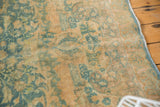 Detail of vintage Persian Khorassan rug: faded blue-green scrolling palmettes on worn gold, secured side.