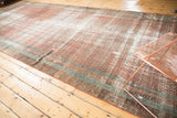 Prominent distressed texture with exposed foundation on an antique Malayer runner in terra cotta and blue.