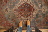 Distressed texture and visible wear on vintage Persian rug with slate blue and wine red medallion.