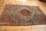 Distressed Northwest Persian rug lower corner, displaying geometric floral botehs and thin border.