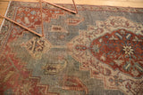 Vintage distressed Northwest Persian rug showing faded geometric floral botehs in slate blue and red.