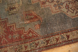 Vintage distressed Northwest Persian rug corner with geometric field, red border, and time-softened hues.