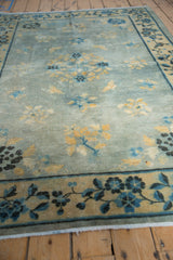 Distressed texture of antique Chinese Peking rug with powder blue field, golden floral motifs, and indigo border.