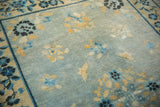Distressed powder blue antique Peking rug field, with soft gold and indigo florals and wear.