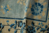 Distressed powder blue, dusty gold floral motifs on a folded Antique Peking rug, with faint foundation showing.