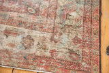 Worn texture of distressed vintage Mahal rug close-up, featuring blush red and ivory tones.