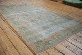 Distressed vintage Agra carpet with aged texture, faded diamond lattice pattern, and visible foundation.