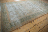 Distressed Agra carpet's faded green border and textured field showing silver and pale gold.