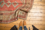 Folded vintage Malayer rug revealing distressed low pile, intricate borders, and soft blue tones.