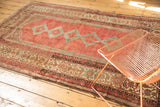 Distressed Malayer rug's cranberry field, blue interlacing geometry, and intricate multi-color borders.