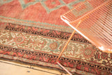 Distressed Persian Malayer rug border with cranberry, ivory, and blue floral patterns.