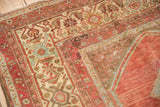 Intricate ivory borders, distressed cranberry field with faint foundation, on a vintage Malayer rug.