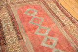 Distressed cranberry red field, powder blue diamond medallions, and patterned border of the vintage Malayer rug.