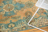 Distressed vintage Persian Tabriz rug with faded gold, powder blue, and brown floral motifs.