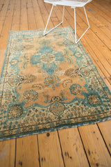 Distressed Tabriz rug corner with blue floral floating border and camel field wear.