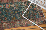 Distressed Sarouk rug corner showing faded floral palmettes and delicate tendrils.
