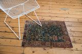 Distressed Sarouk rug, low pile showing ornate faded red and blue floral motifs.