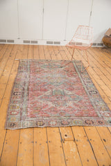 Distressed corner of antique Caucasian Soumac rug, showcasing geometric patterns and blush red tones.