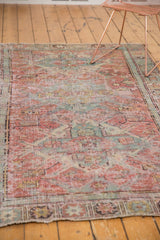 Distressed pile texture with blush red and pale blue geometric patterns on the Soumac rug.