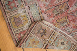 Distressed antique Caucasian Soumac rug corner with worn geometric patterns in blush and pale gold.