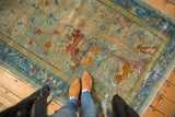 Distressed antique Peking rug showing pictorial motifs, cloudband border, seafoam and bronze tones.
