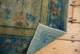 Antique Peking rug corner reveals hand-knotted foundation and distressed pile with blue-green hues.