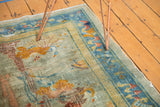 Distressed corner of a Peking rug, with seafoam field, blue cloudband border, and visible foundation.
