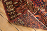 Vintage Turkmen rug's folded corner reveals hand-knotted back, geometric patterns, and fringe.