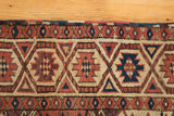 Antique Beshir carpet detail: terracotta, navy, ivory geometric motifs, with secured edge.