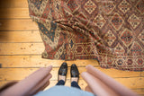 Folded antique Beshir carpet section with repeating lattice panels in terracotta, navy, and ivory.